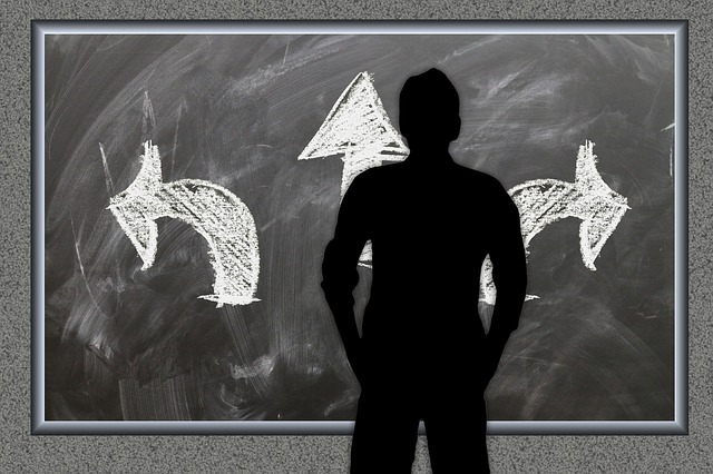 man's silhouette in front of a chalkboard with arrows pointing in different directions