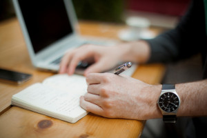 man's hands jotting down the business plan and financial goals
