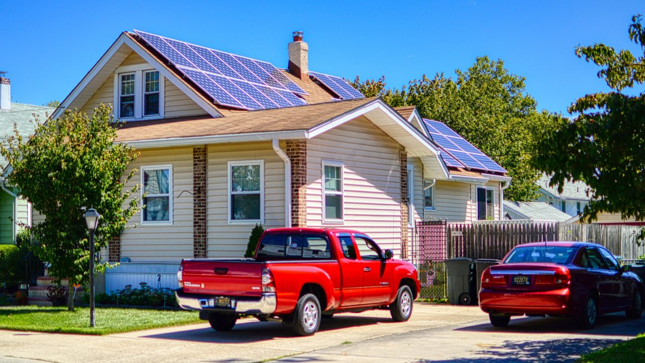a house with a two red cars parked outside and solar panels on the roof