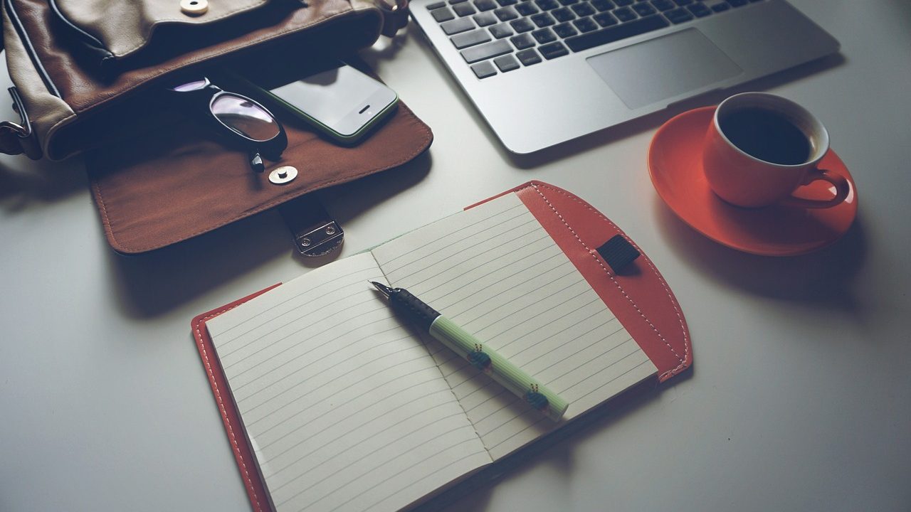 doctors briefcase sprawled out next to laptop, notebook and coffee