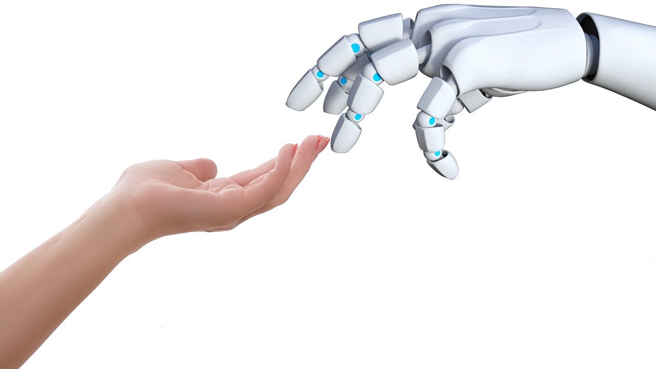 a robot hand gently touching the fingers of a human hand