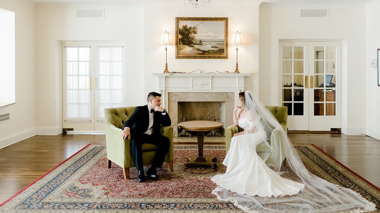 a groom and bride sitting in opposite chairs staring thoughtfully at each other