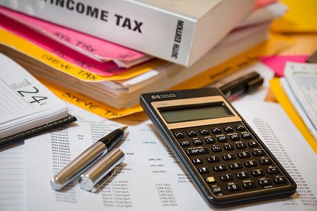 calculators, pens and binders stacked that say income tax