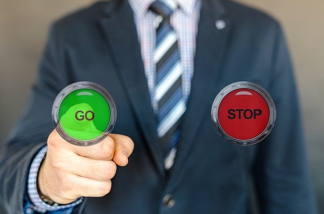 a man in a business suit, pressing a 'go' button instead of 'stop'.