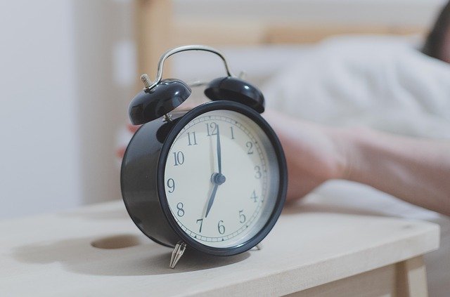an alarm clock beside a bed