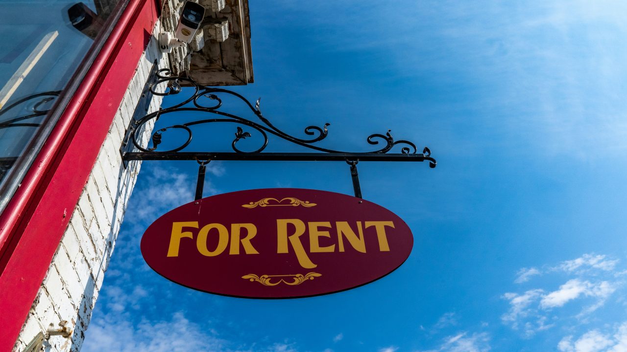 a for rent sign hanging outside a british like building