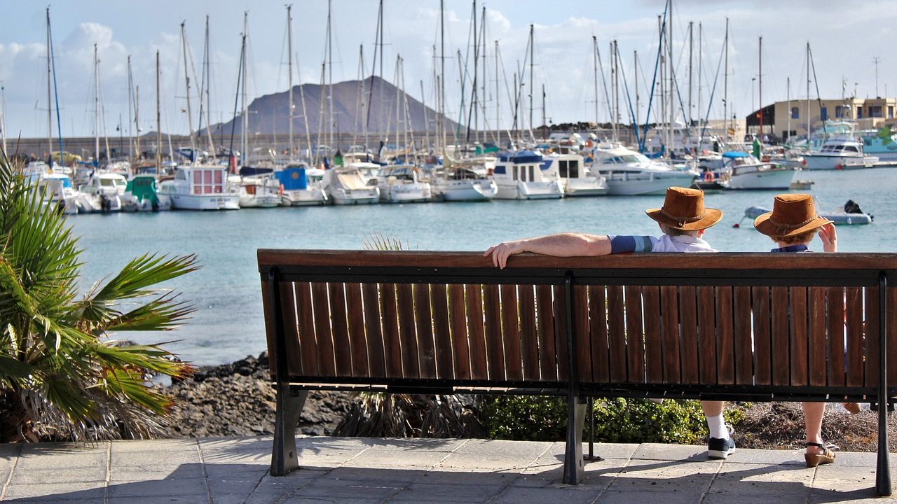 elder couple sitting on a bench overlooking docks