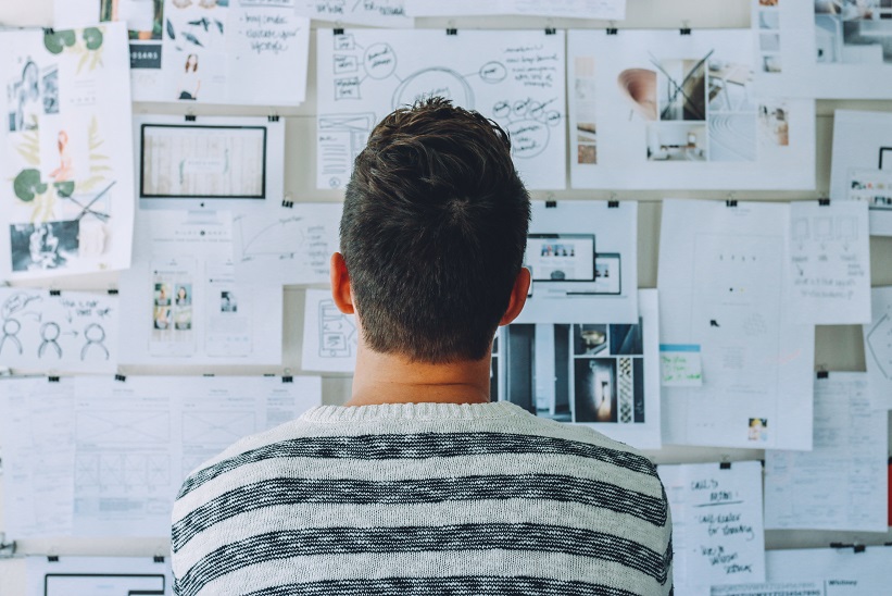 man looking at whiteboard with many brainstorming ideas