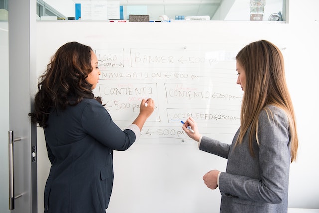 two business people writing on a white board as it relates to the web