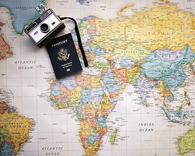 passport and camera on top of a world map