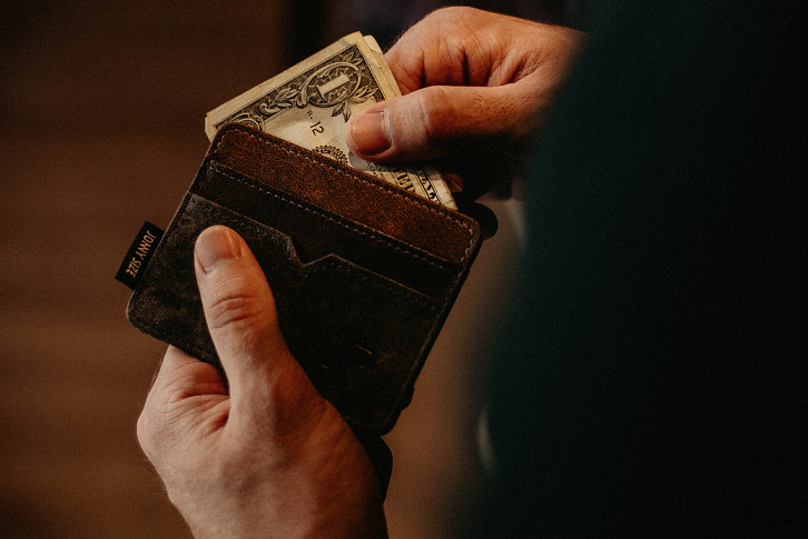 man pulling out dollar bills from his wallet